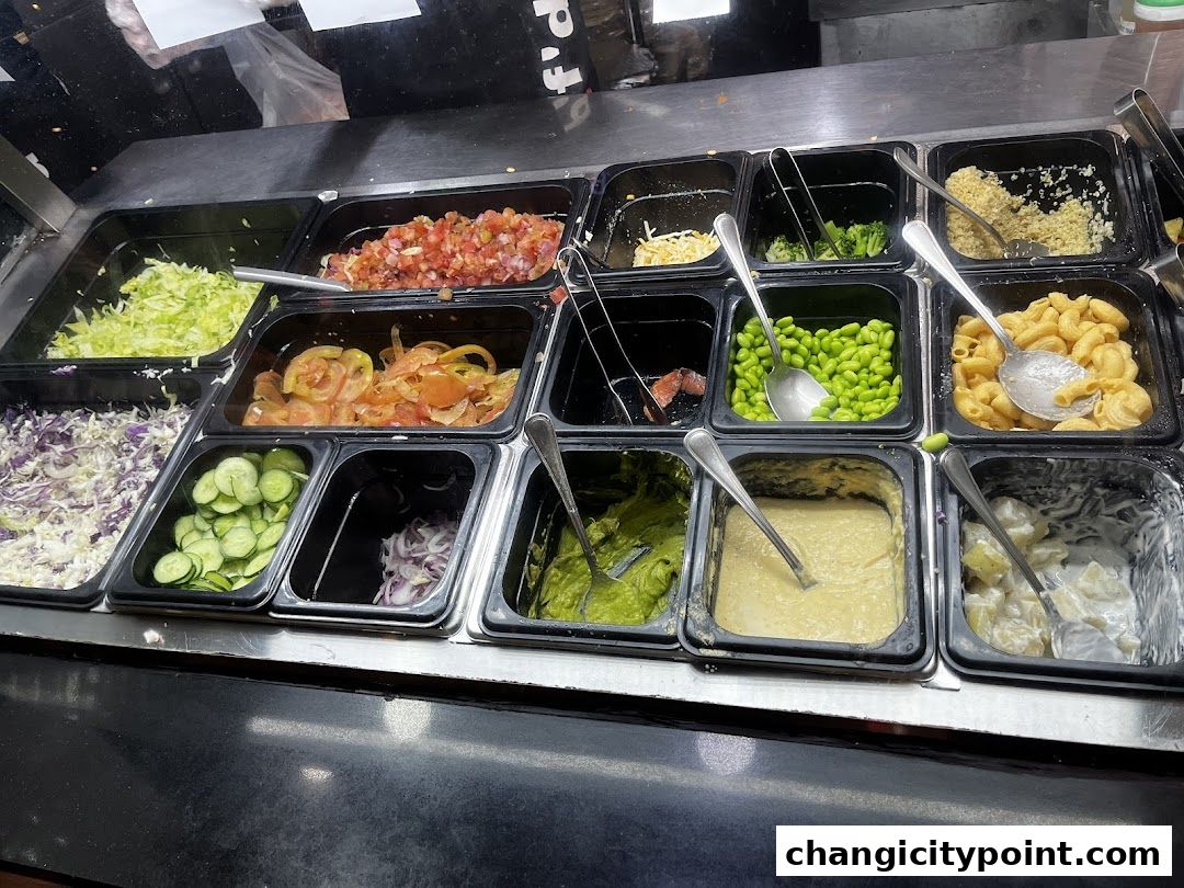 A display of fresh salad bar ingredients including chopped vegetables, grains, and pasta.