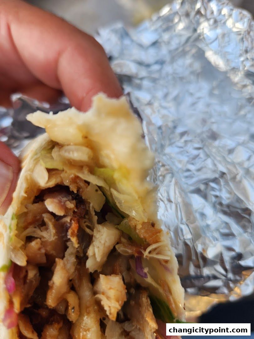 A close-up shot of a delicious wrap being held, revealing its savory fillings.