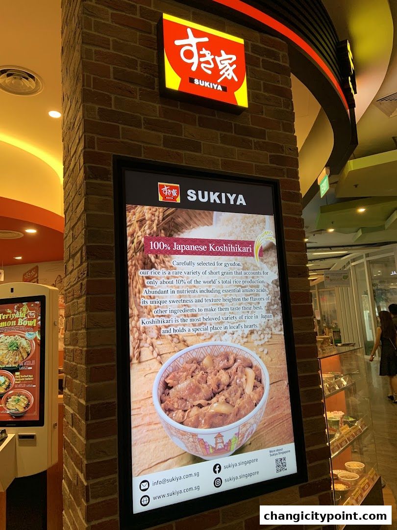 Sukiya Gyudon restaurant storefront with a large digital display showcasing Japanese rice and a bowl of gyudon.