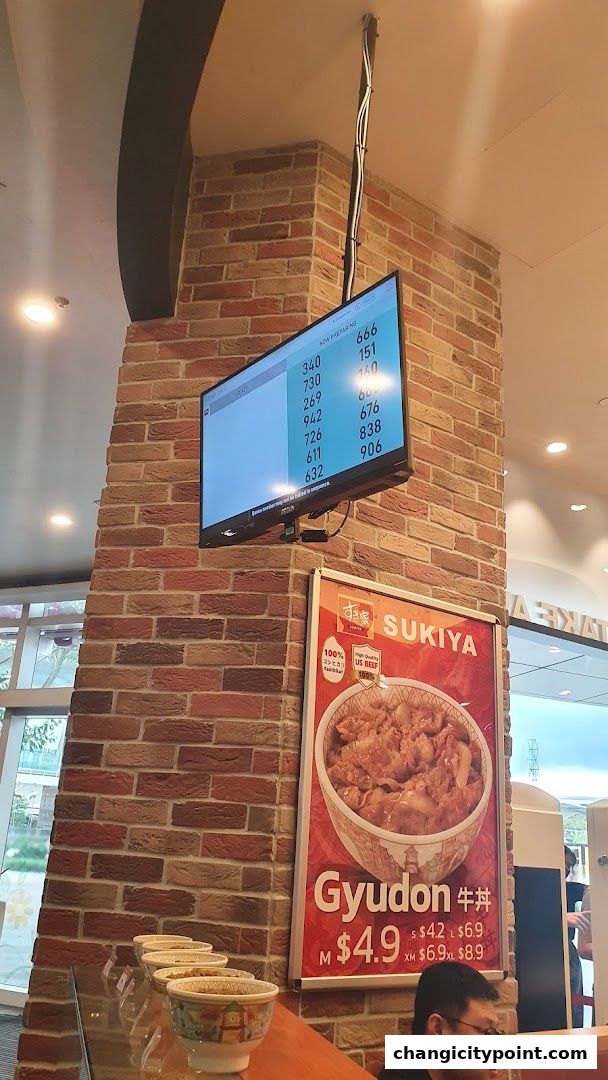 Sukiya Gyudon restaurant interior with a digital display and a poster of Gyudon.