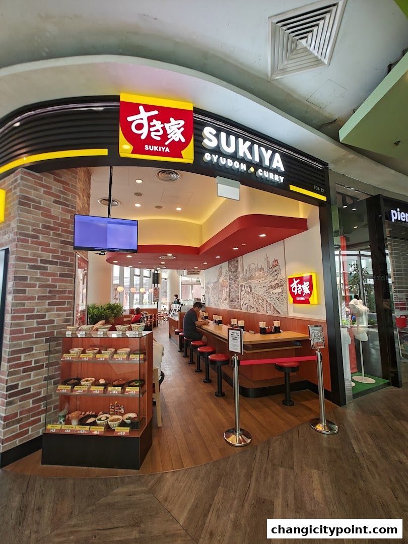 Exterior view of Sukiya Gyudon Curry restaurant with display cases and seating.