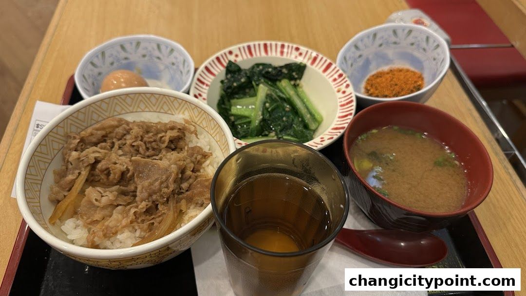 A delicious Sukiya Gyudon set meal with beef bowl, soup, vegetables, and a drink.