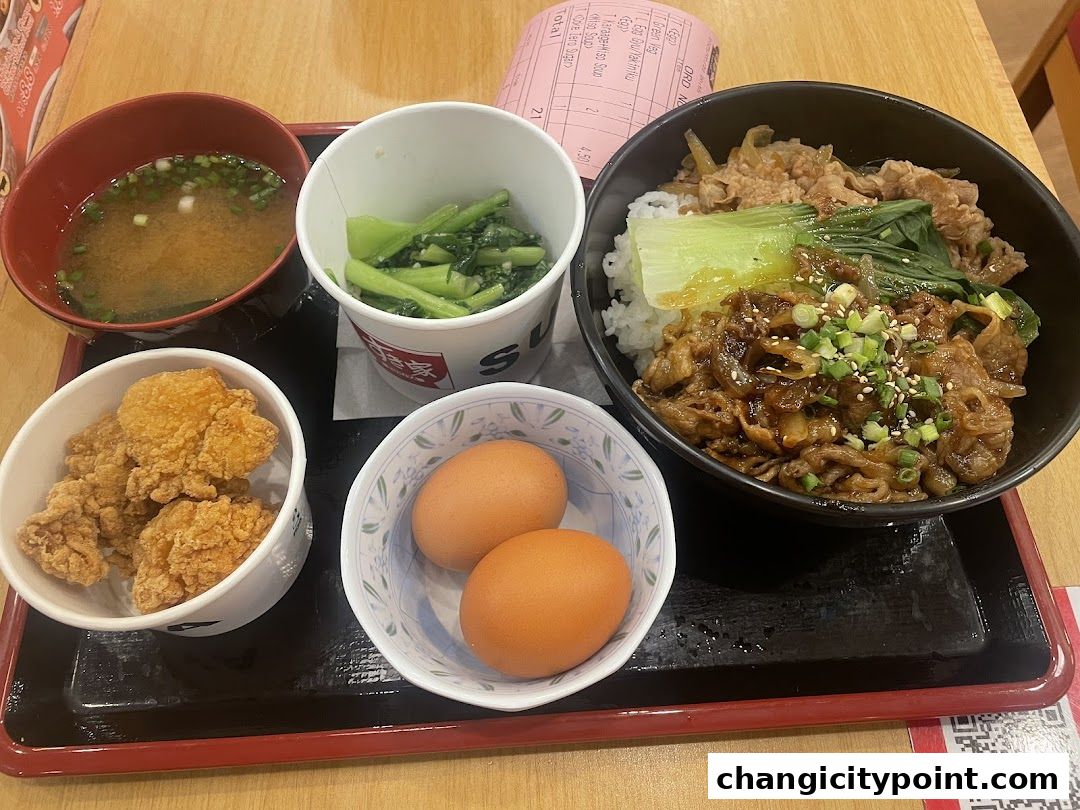 A meal set with gyudon, fried chicken, miso soup, vegetables, and eggs.