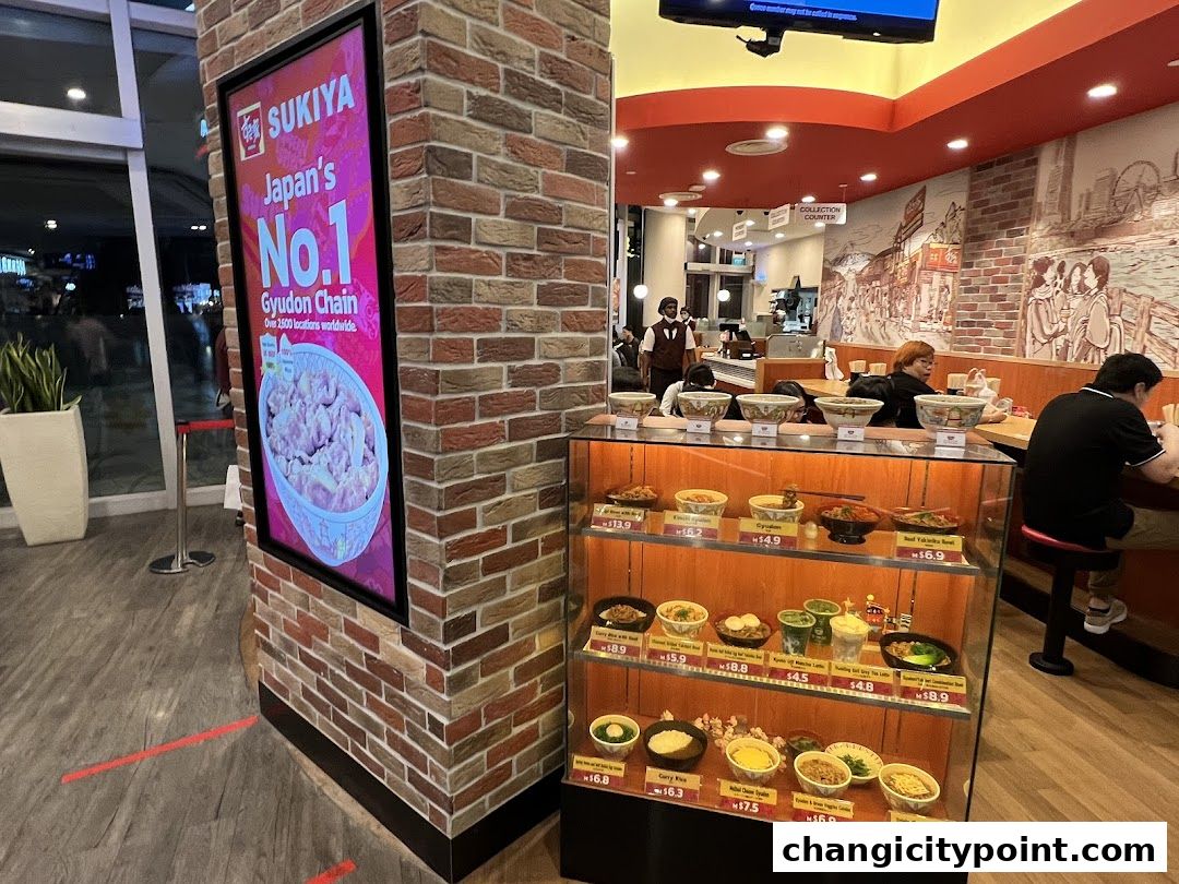 Sukiya Gyudon restaurant interior with food display and customers dining.