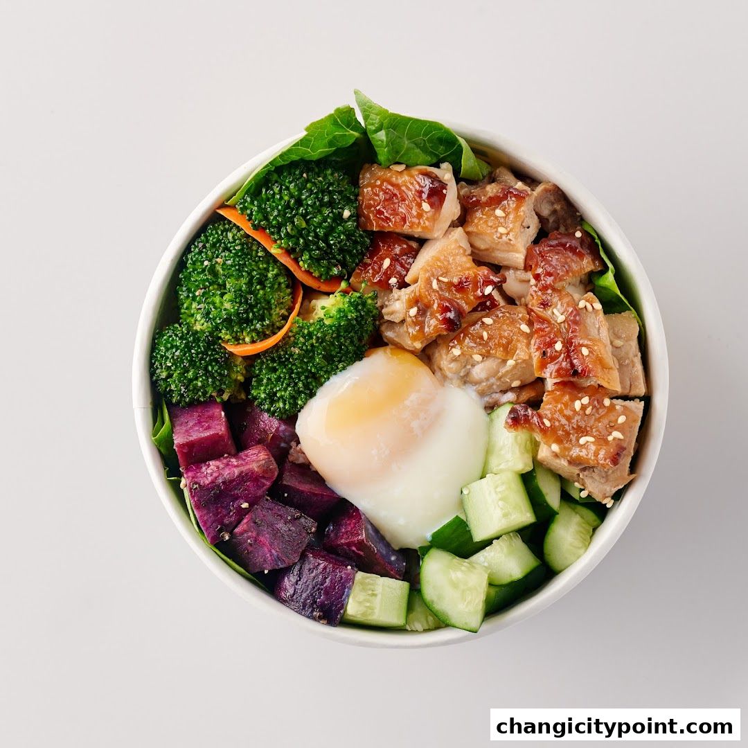 A healthy and colorful poke bowl with chicken, egg, broccoli, sweet potato, and cucumber.