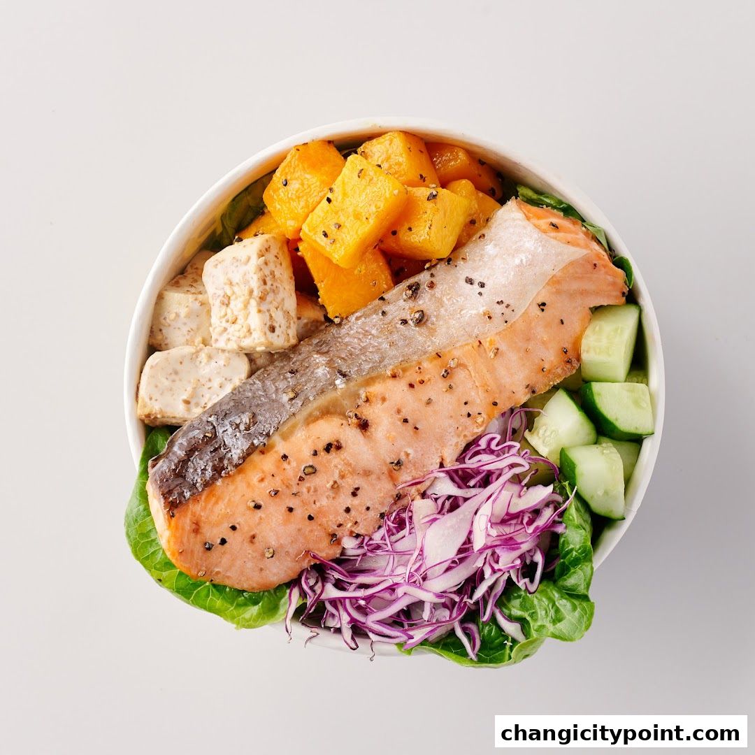 A healthy salmon poke bowl with fresh vegetables and roasted pumpkin.