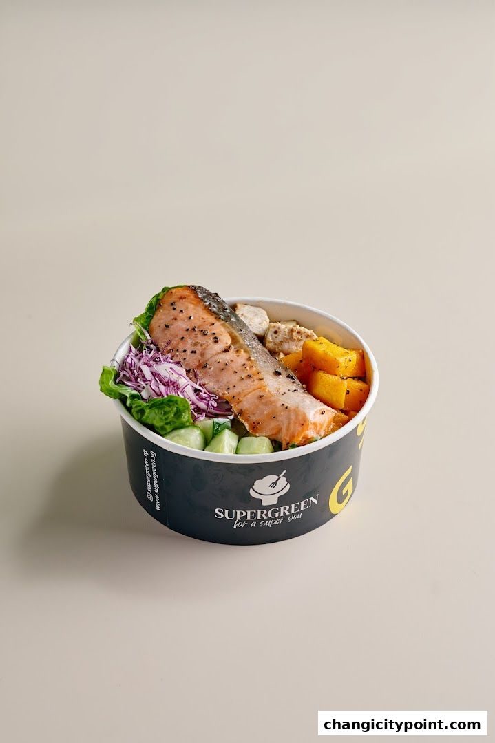 A healthy salmon salad bowl from Supergreen with fresh vegetables and roasted pumpkin.