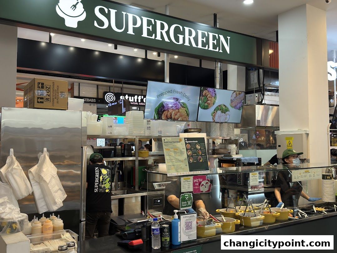 Interior view of Supergreen, a healthy food shop with staff preparing meals.