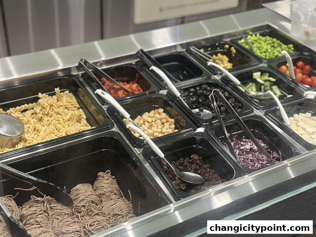 A display of various salad bar ingredients including pasta, noodles, vegetables, and toppings.