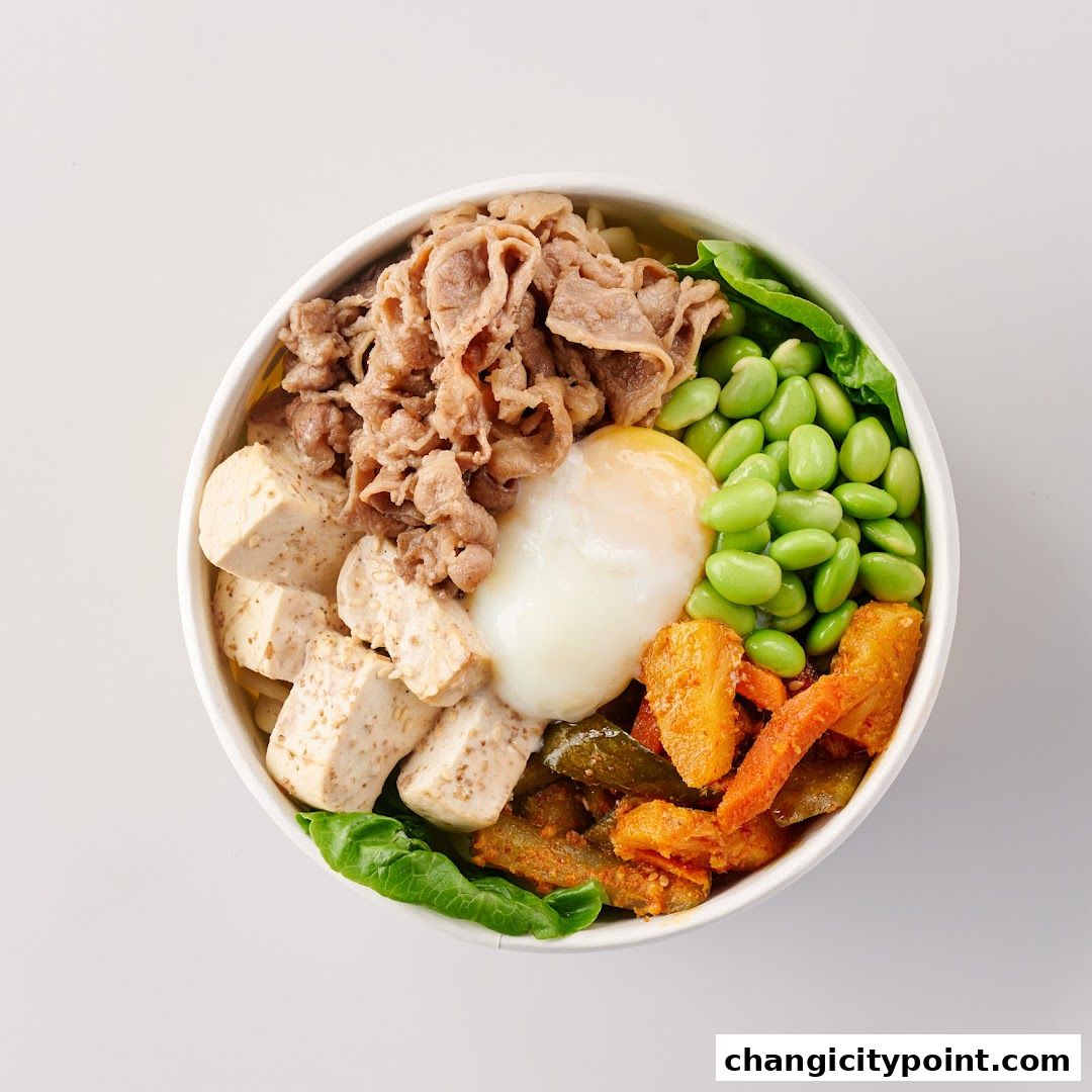 A delicious bowl of food with beef, tofu, egg, edamame, and vegetables.