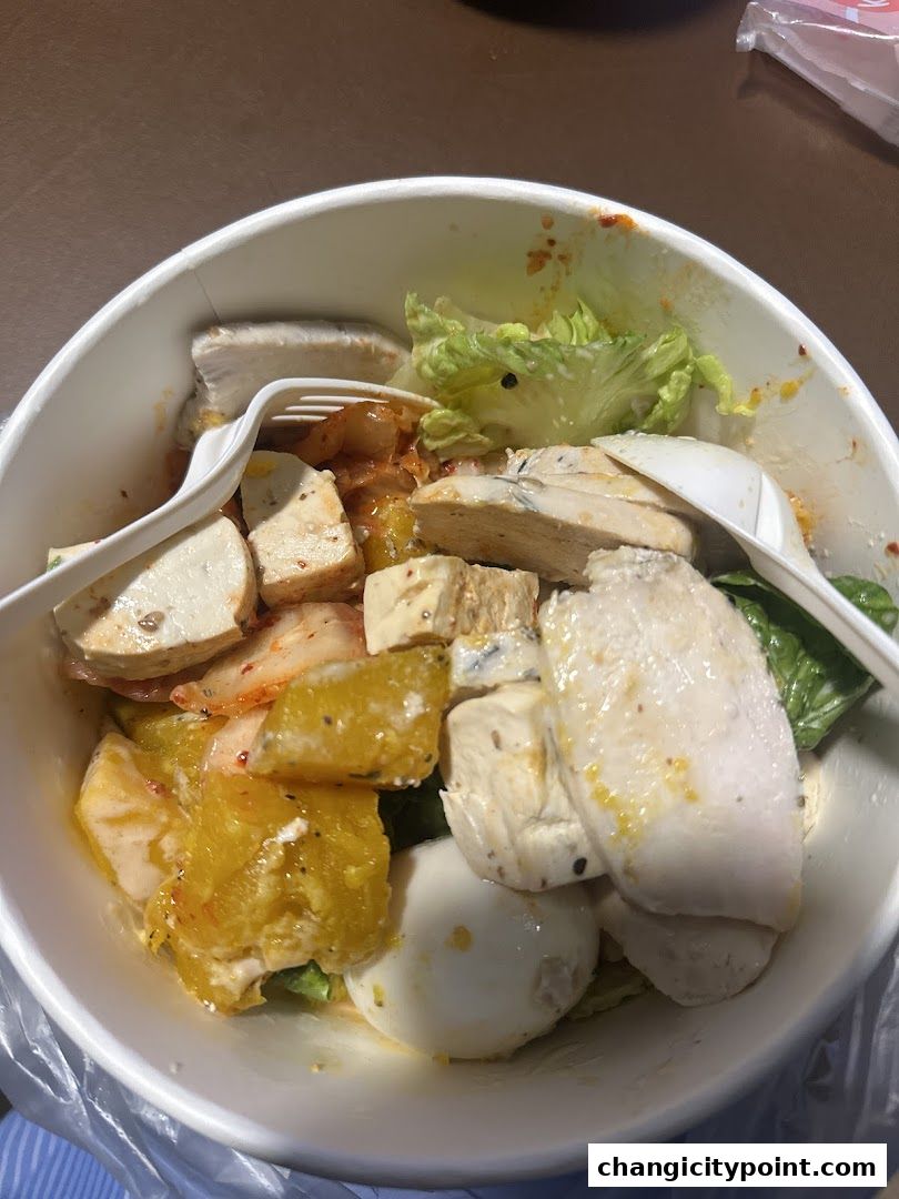 A close-up of a healthy salad bowl with chicken, eggs, and vegetables.