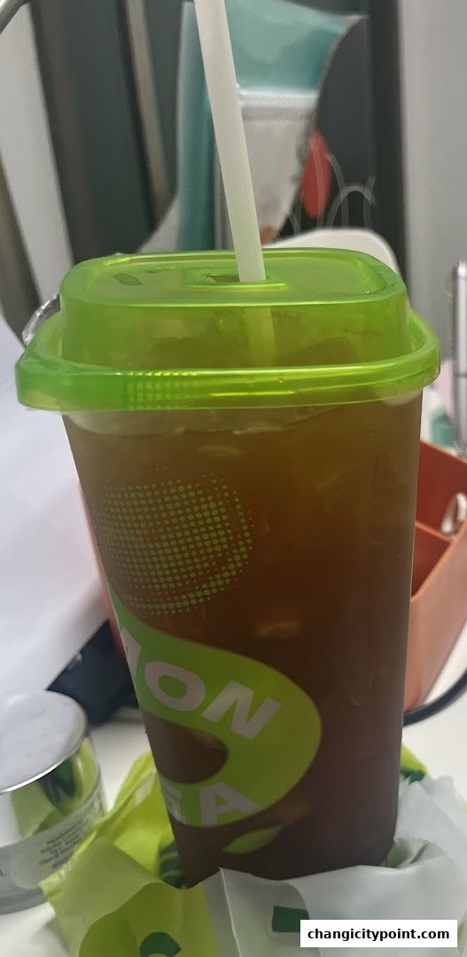 A refreshing iced tea with a green lid and straw from Taning.