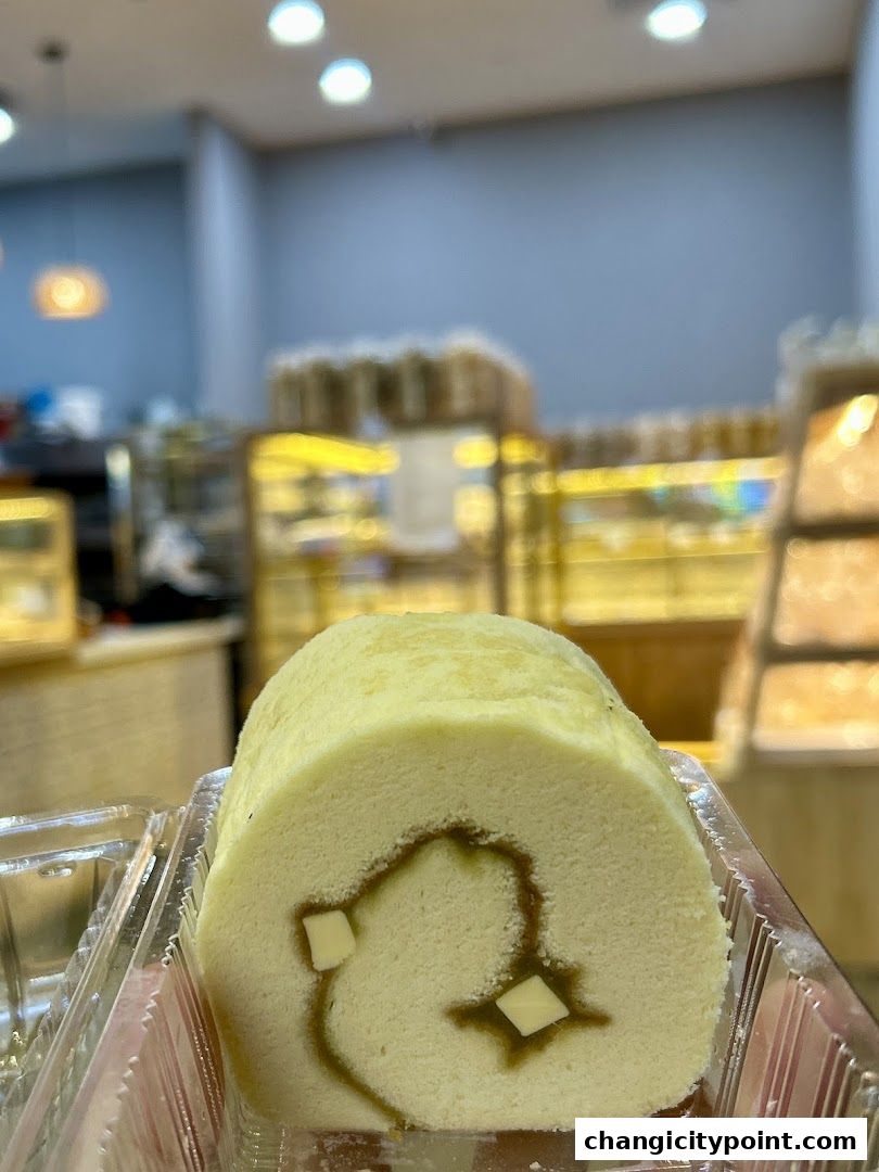 A close-up of a Swiss roll cake with filling and cream cheese cubes in a plastic container.