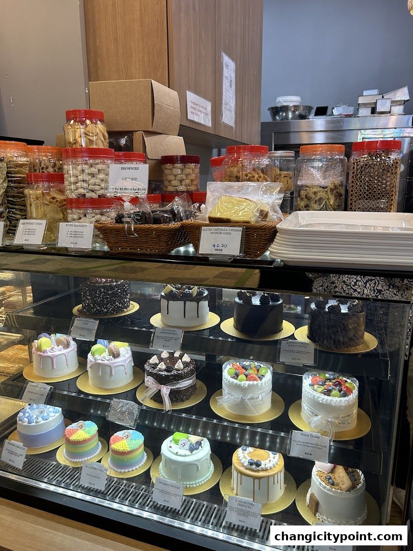 A display case filled with various cakes and baked goods from Thai Baang Bakery.