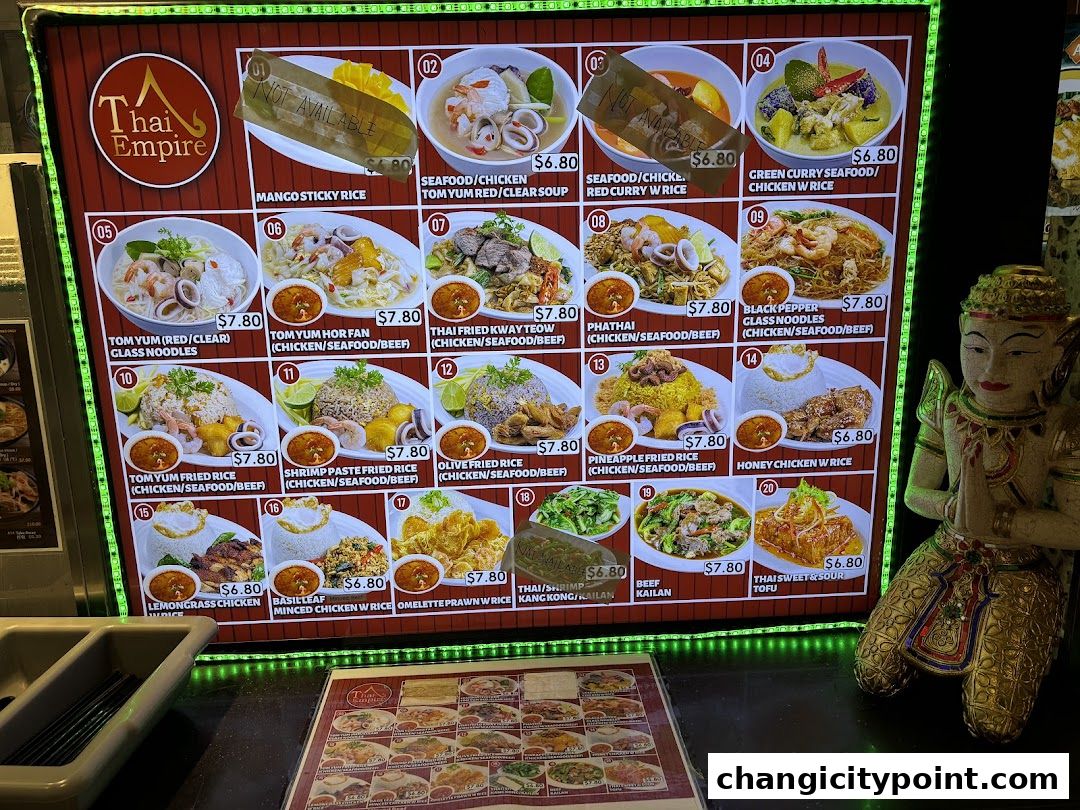 A brightly lit menu board displaying various Thai dishes with prices and images.