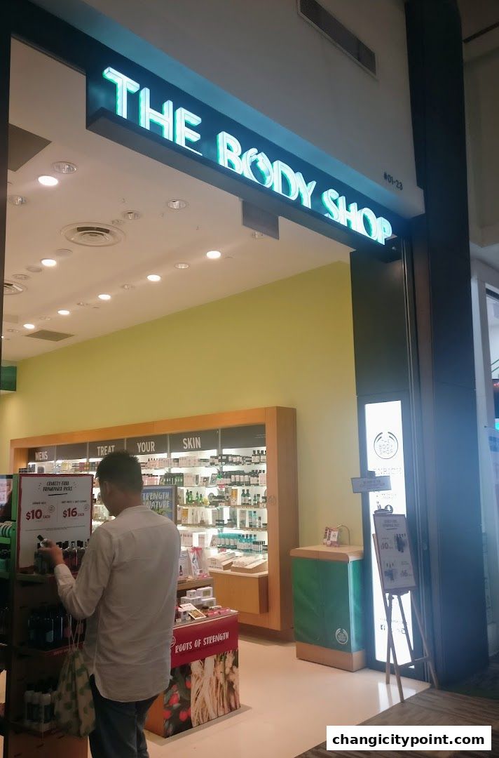 The Body Shop storefront with illuminated signage and displays of skincare products.
