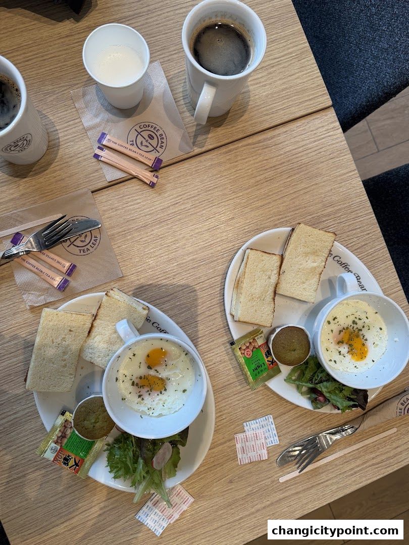 Two breakfast plates with eggs, toast, and salad, alongside coffee and milk.