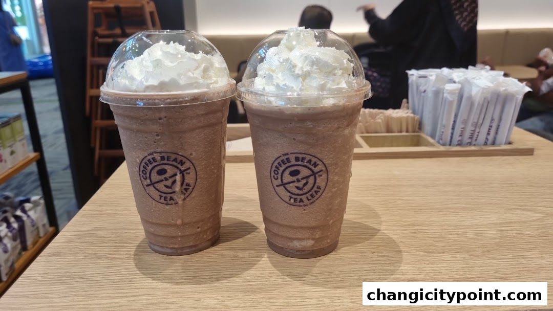 Two iced coffee drinks with whipped cream on a wooden table at The Coffee Bean & Tea Leaf.