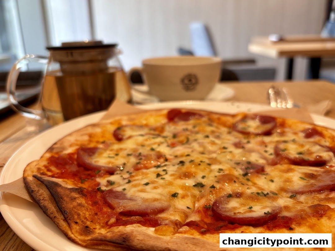 A close-up of a pepperoni pizza with a teapot and cup in the background.
