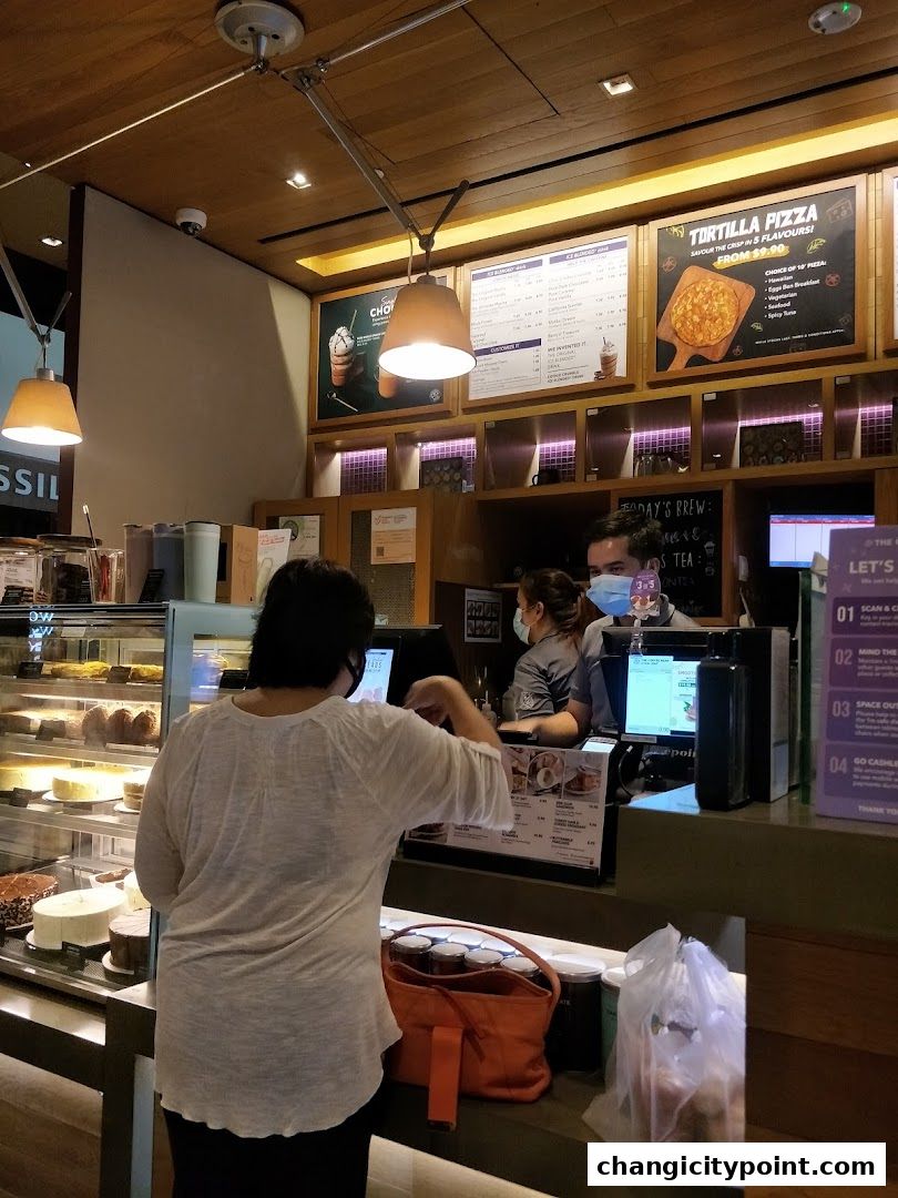 Customers ordering at the counter of The Coffee Bean & Tea Leaf with cakes on display.