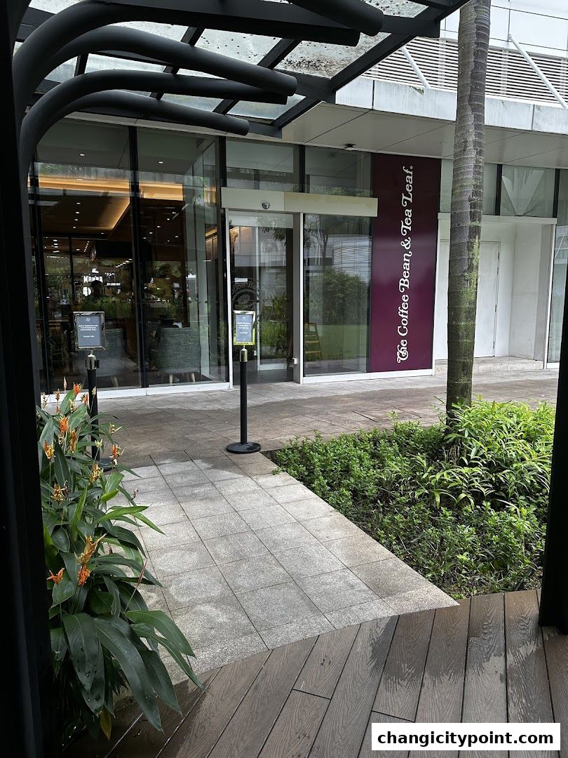 Exterior view of The Coffee Bean & Tea Leaf shop with plants and seating area.
