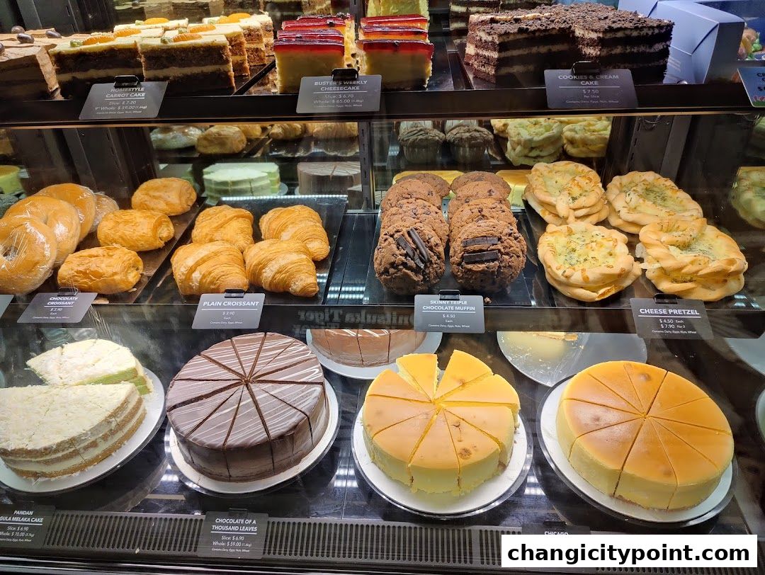 A display case filled with various cakes, pastries, cookies, and pretzels.