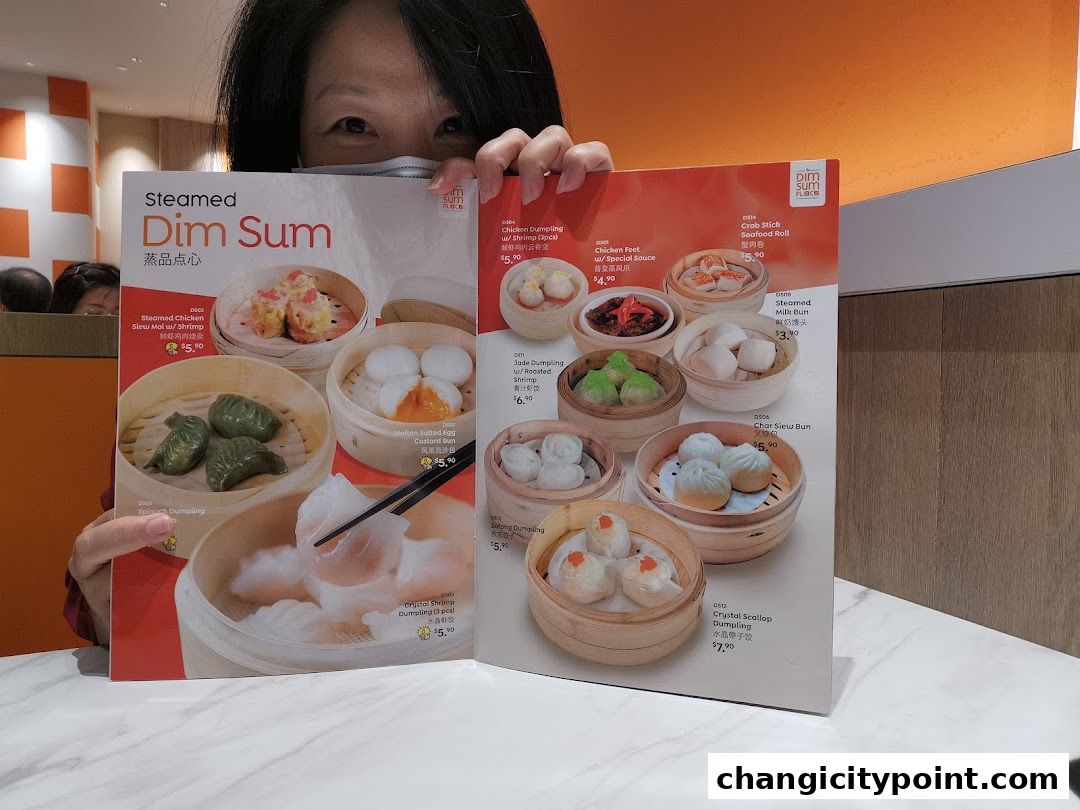 A person holds up a menu showcasing various steamed dim sum dishes with prices.