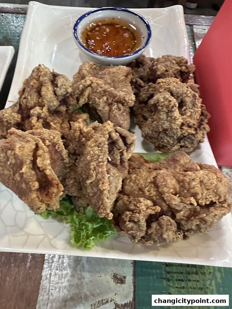 A plate of crispy fried chicken pieces served with a small bowl of dipping sauce.