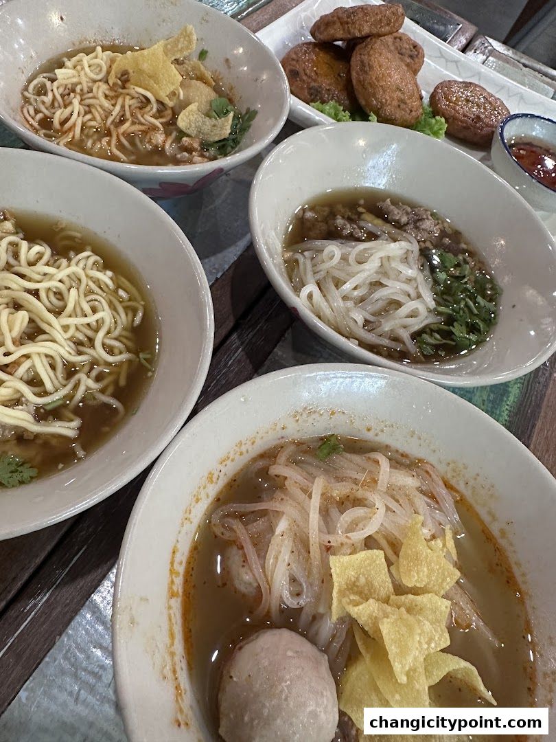 A close-up shot of several bowls of noodle soup and fried snacks.