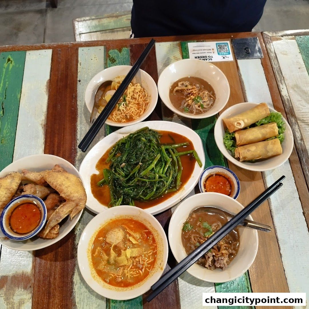 A table laden with various dishes from The Original Boat Noodle, including noodles, spring rolls, and stir-fried vegetables.