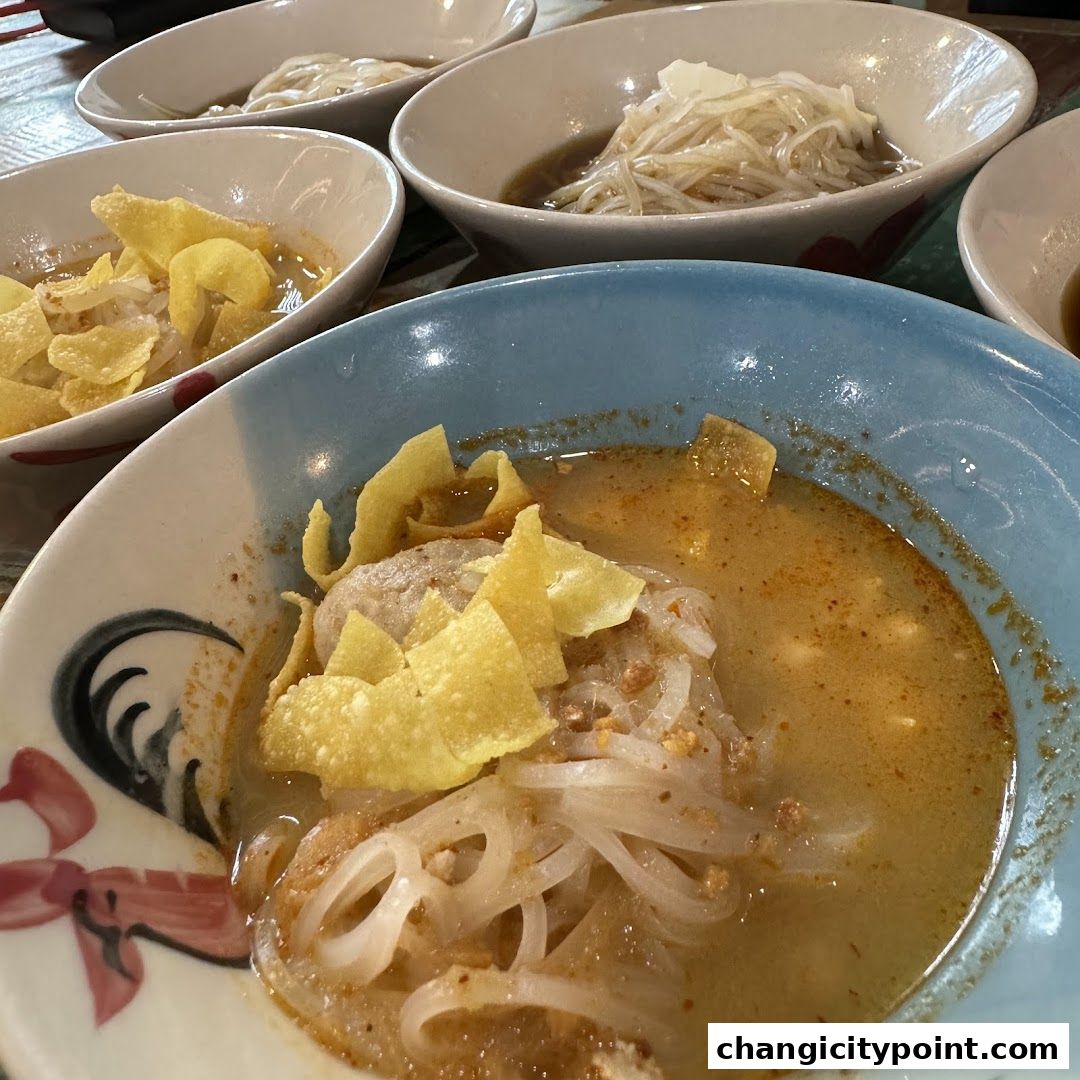 Close-up of several bowls of boat noodles with crispy wonton toppings.