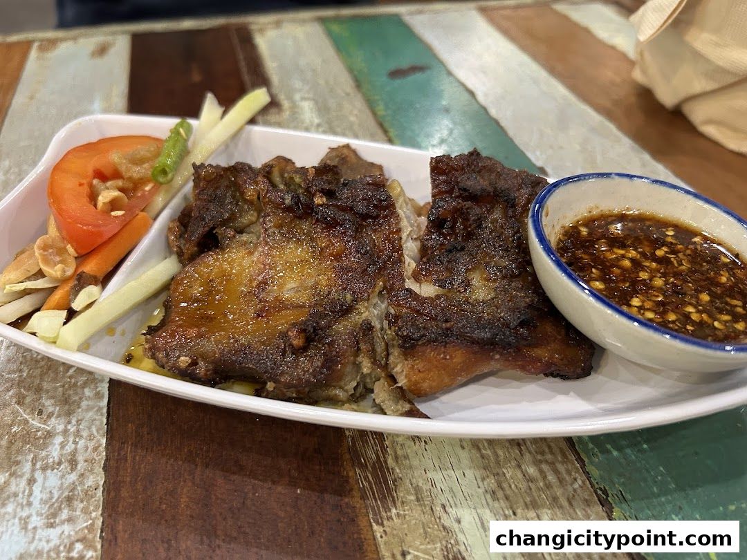 A plate of grilled meat with a side of vegetables and dipping sauce.