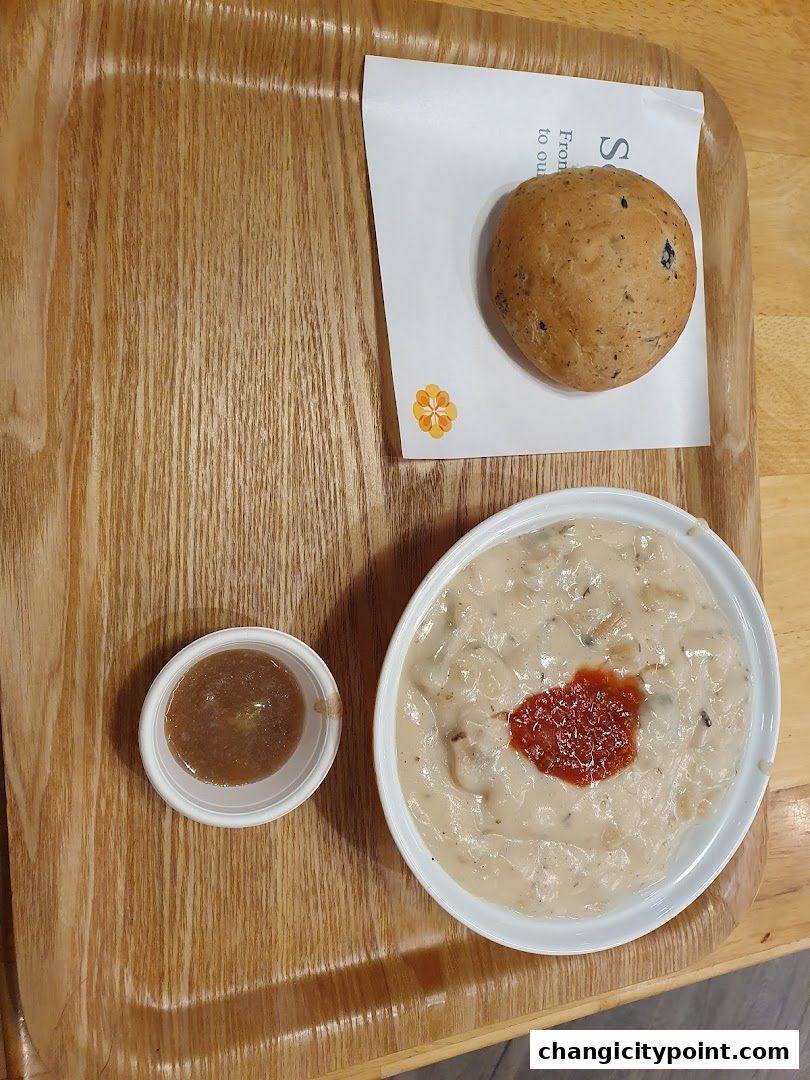 A bowl of creamy soup with a dollop of tomato paste and a side of bread.