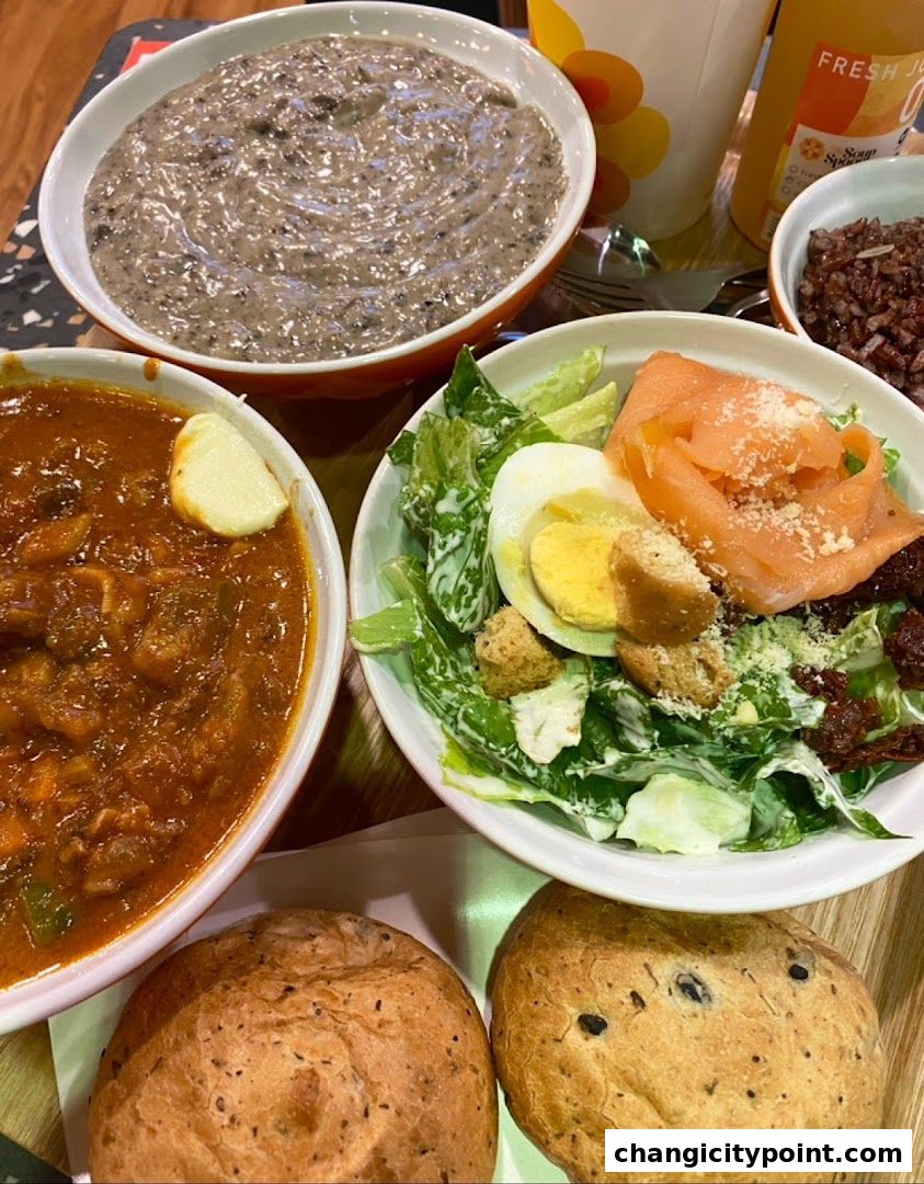 A close-up of a meal featuring soup, salad, rice, and bread.