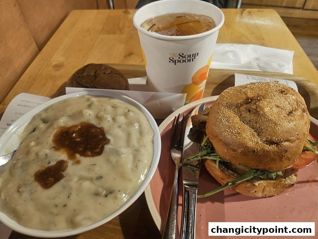 A meal from The Soup Spoon Union featuring soup, a burger, a cookie, and a drink.
