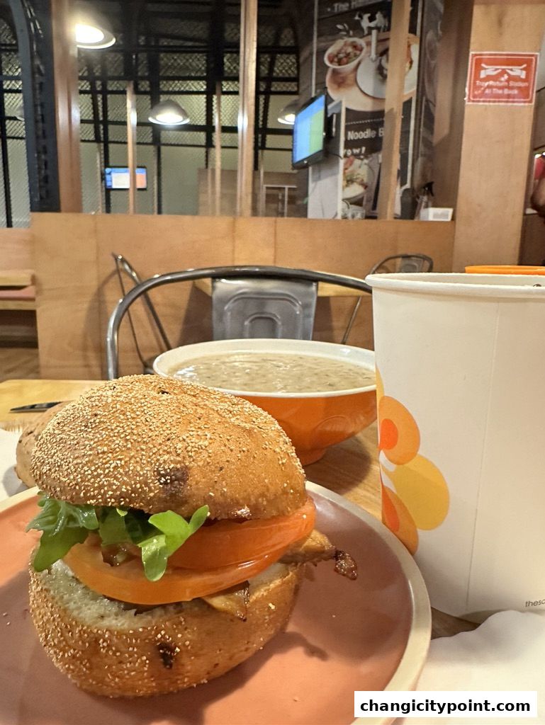A close-up of a burger and a bowl of soup on a table at The Soup Spoon Union.