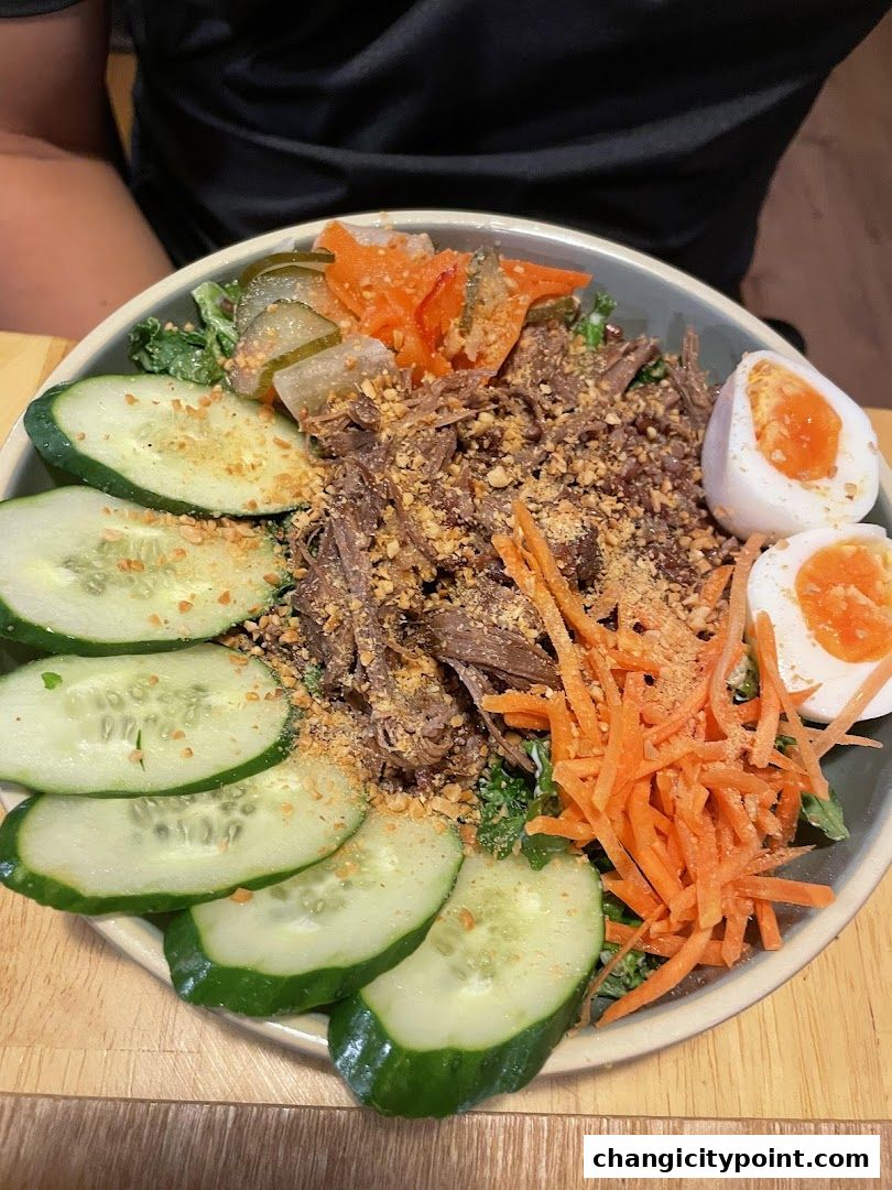 A bowl of shredded meat salad with cucumber, carrots, pickles, and boiled eggs.