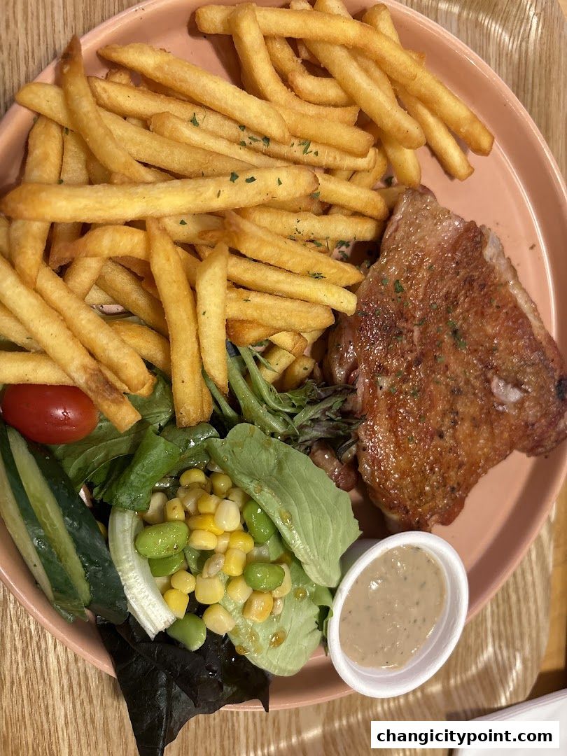 A plate of crispy fries, grilled chicken, and a fresh salad with dressing.