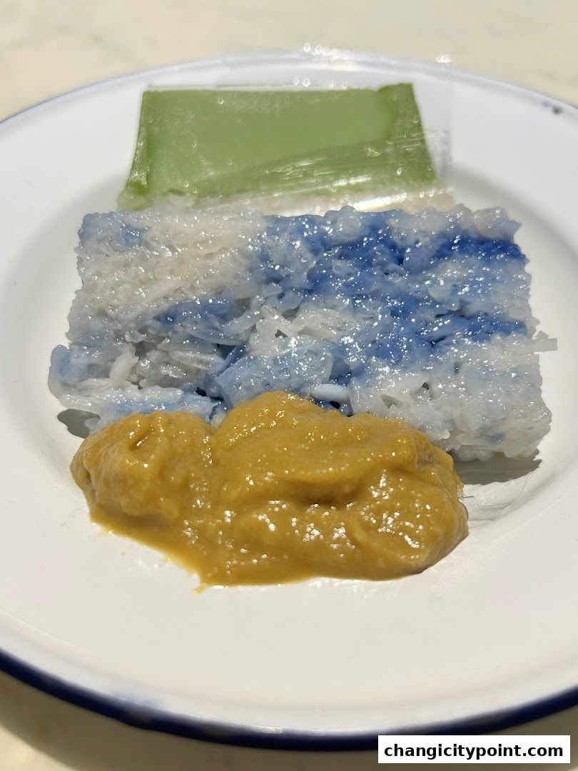 A plate of colorful traditional Asian desserts, including blue and white sticky rice and green jelly.