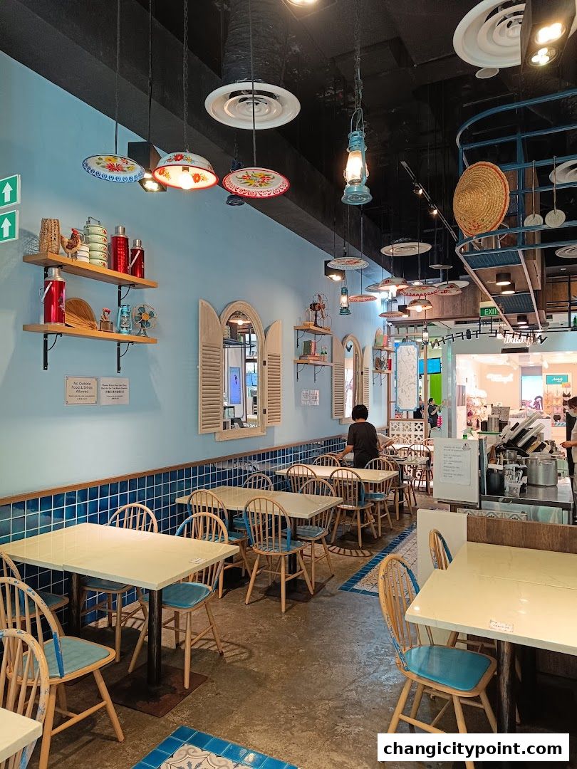 Interior of a brightly lit restaurant with blue walls, wooden tables, and chairs.