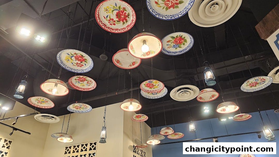 Decorative ceiling lights and plates with floral patterns hang in a restaurant.