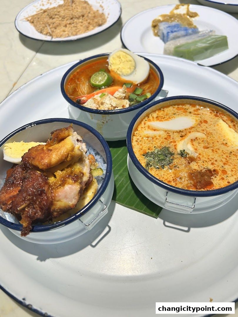 A close-up of three bowls of food, including laksa and chicken, served on a large white platter.