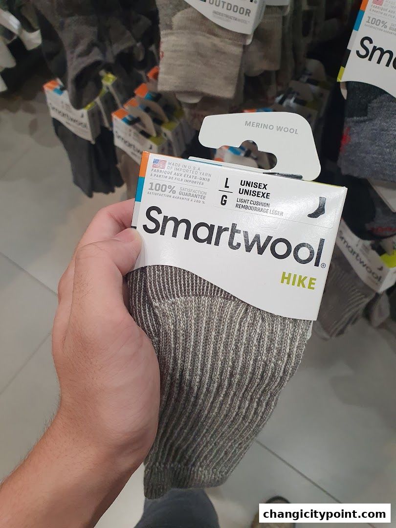 A hand holds a pair of Smartwool hiking socks with merino wool.