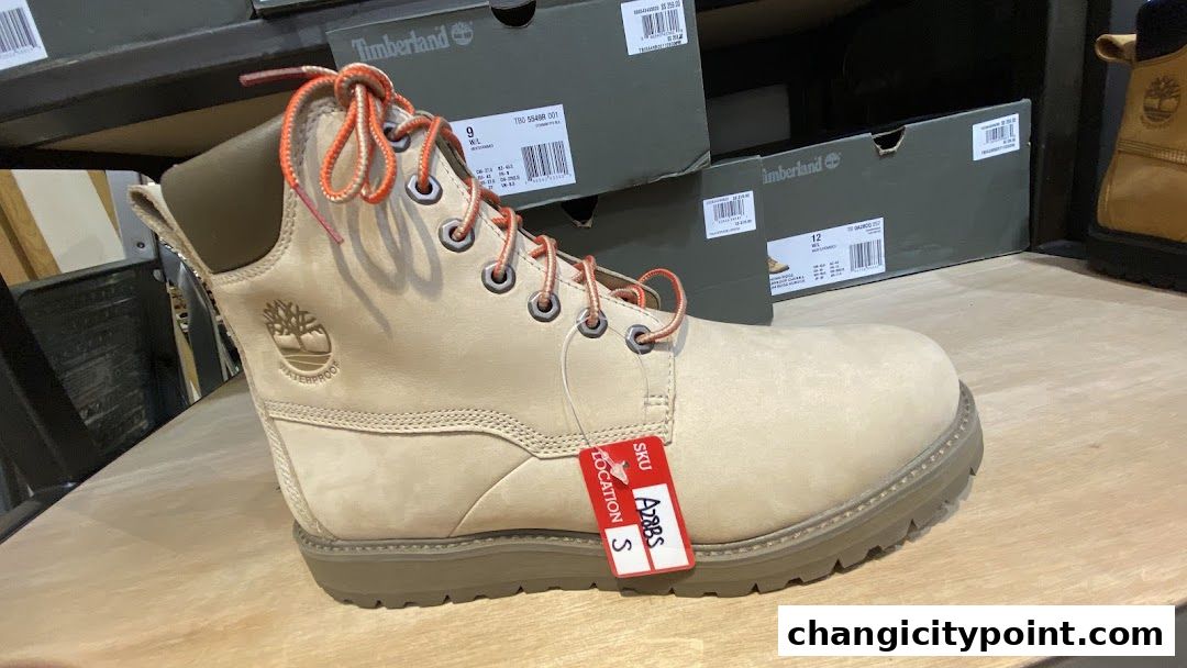 A close-up of a tan Timberland boot with orange laces and a price tag.