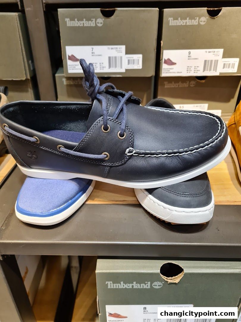 A close-up of navy blue Timberland boat shoes on a shelf with shoe boxes.