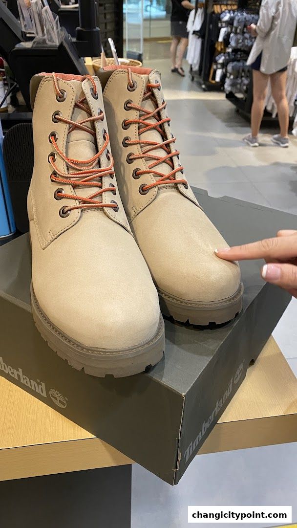 A close-up of beige Timberland boots with orange laces on a shoebox.