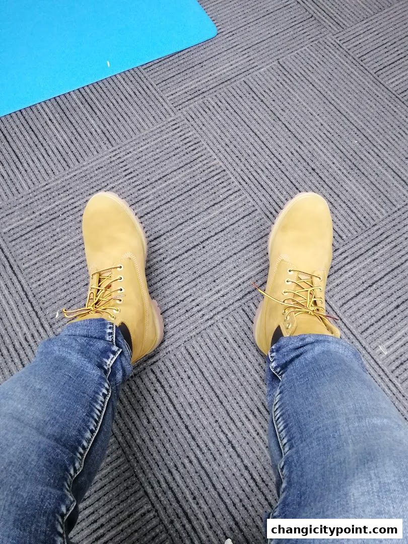 A person wearing classic Timberland boots and blue jeans on a carpeted floor.