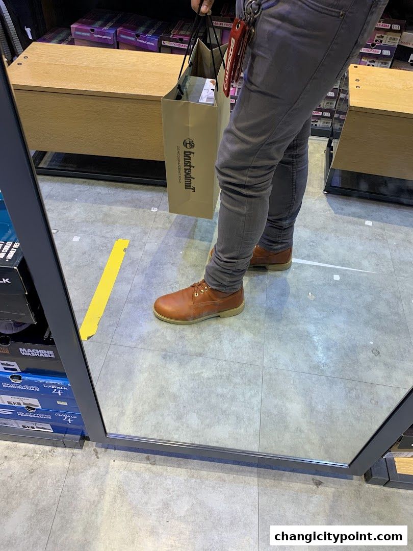 A person wearing Timberland shoes and holding a Timberland shopping bag.
