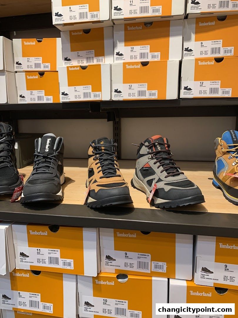 Timberland boots and shoe boxes are displayed on shelves in a retail store.