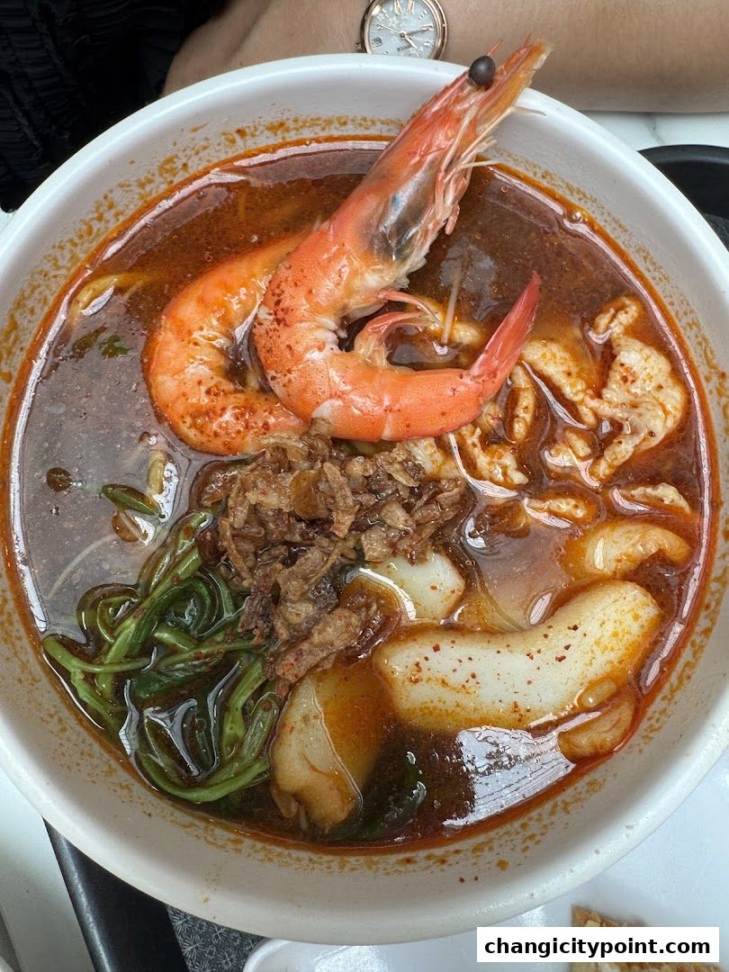 A close-up shot of a steaming bowl of prawn noodle soup with two large prawns.